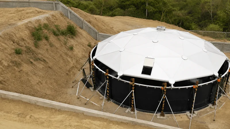 White geodesic dome cover installed on a black bolted industrial tank at a mining site