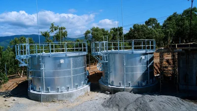 two installed stainless steel bolted tanks with ladders and safety railings
